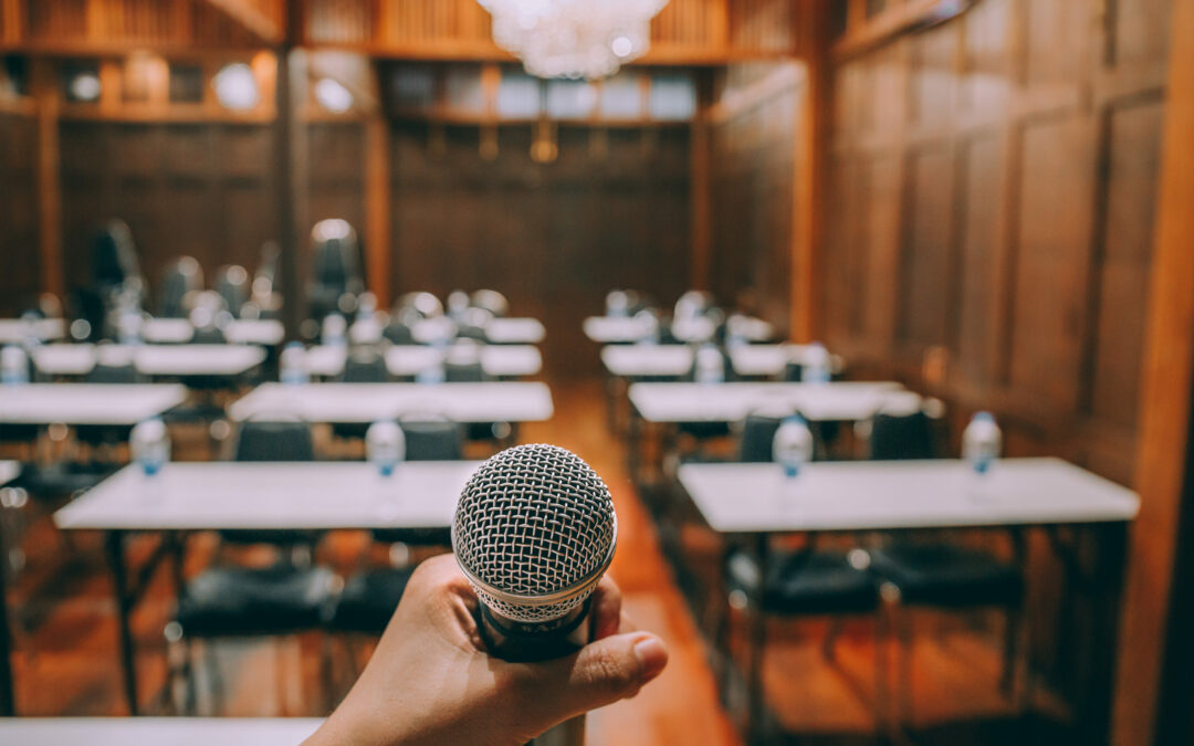 Close-up microphone with blurred people attending seminar background. Vintage process.