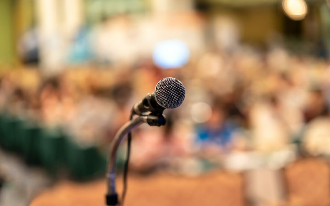 Microphone over the Abstract blurred photo of conference hall or